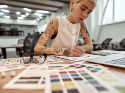 Creative business woman at work. Young and beautiful female web designer making a sketch while sitting at her workplace in the office